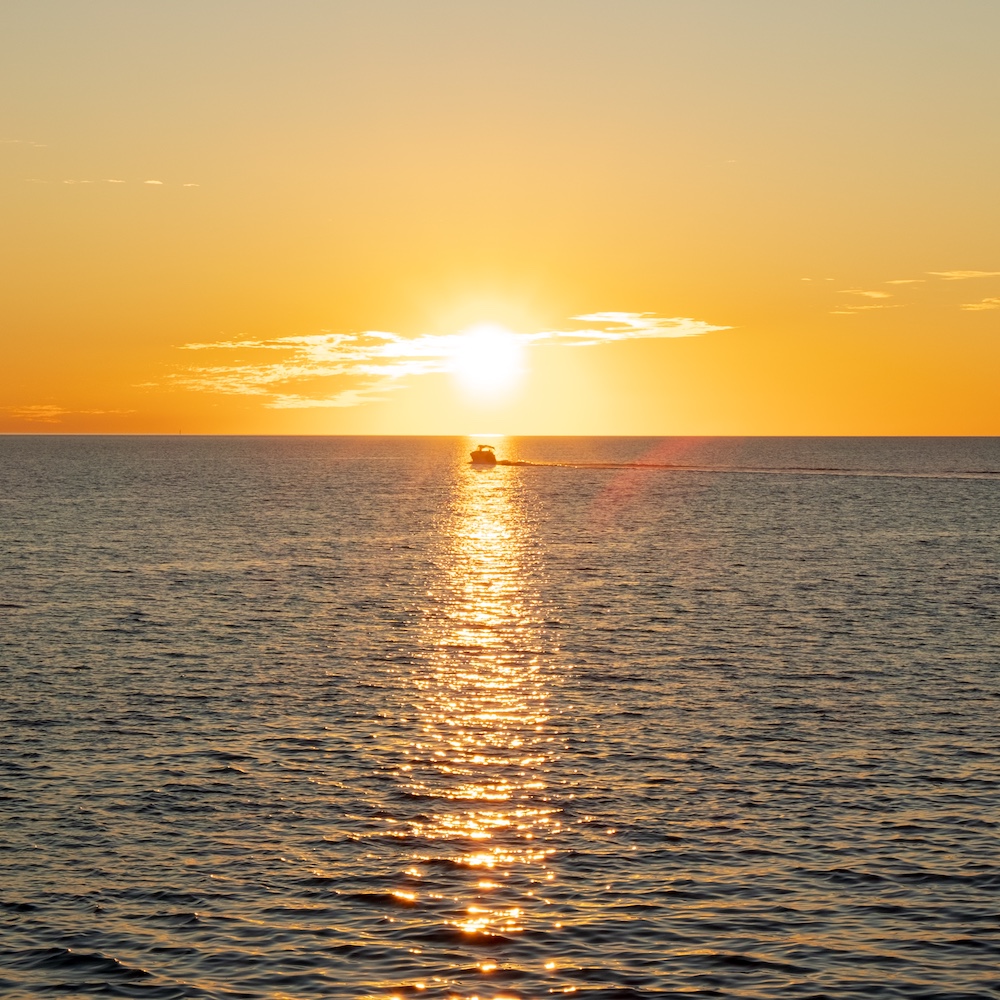 A fishing boat in front of the setting sun.